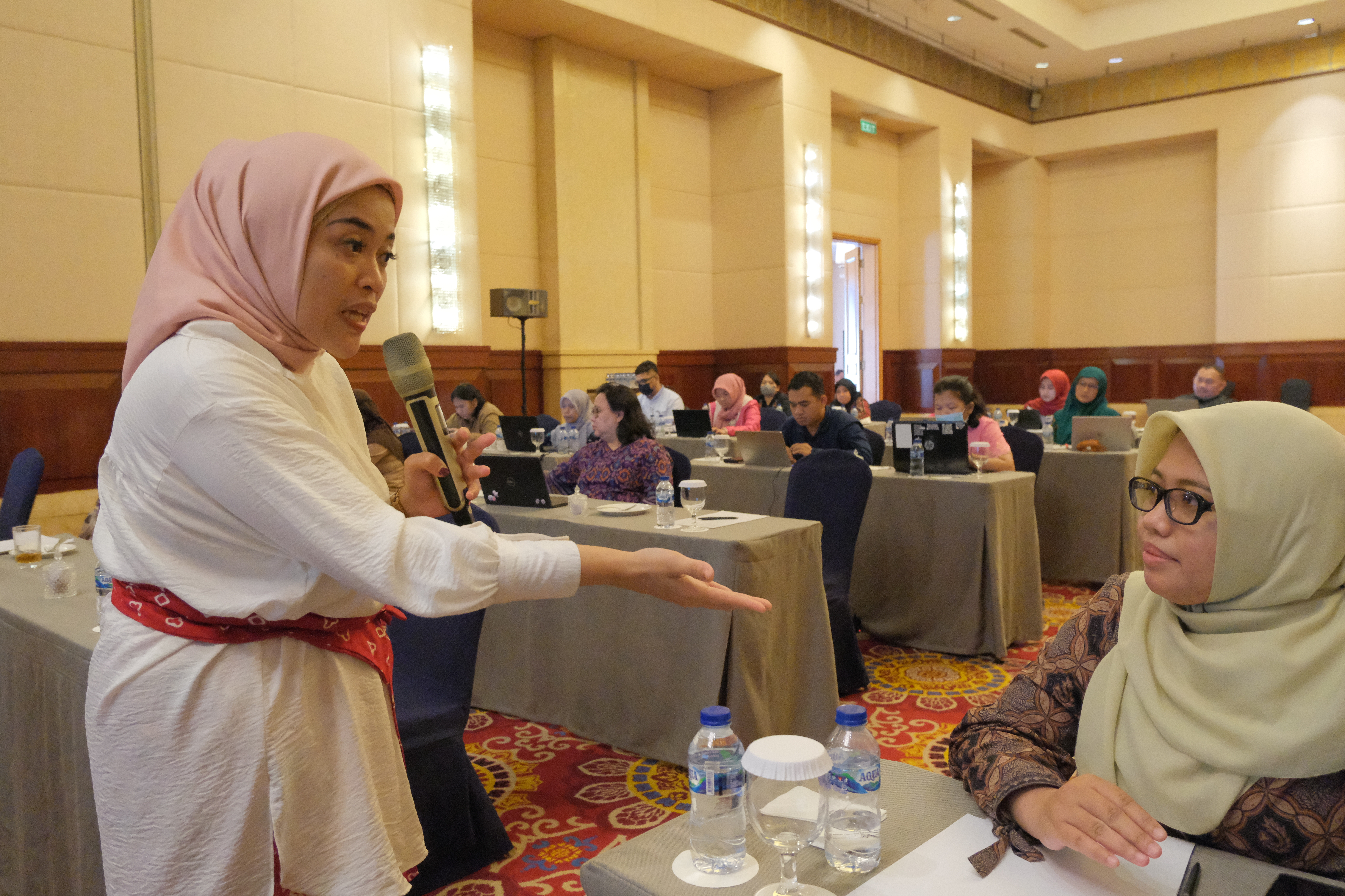 Two women speak to each other at a data quality assurance workshop.