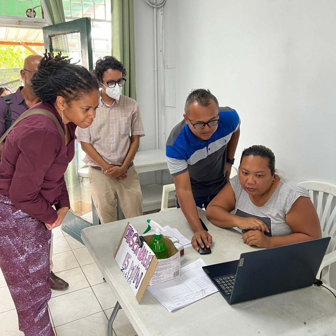 Photo of five people working on a laptop