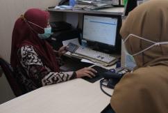 Health worker entering data into electronic medical record in a health facility in East Java, Indonesia. 