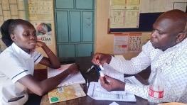 A mentor discusses data quality for malaria commodities with a health worker in Kenya. 