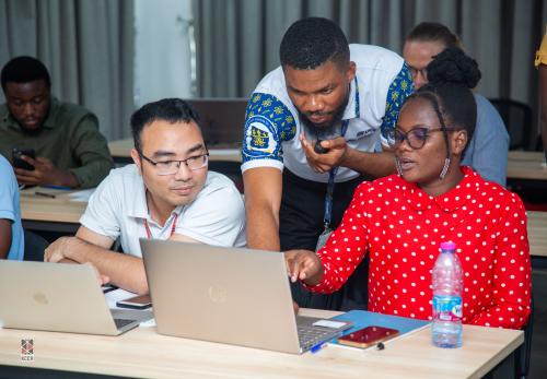 Three people look at a laptop